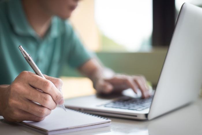 man on laptop taking notes