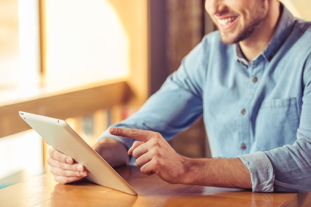 man smiling while pointing at his tablet