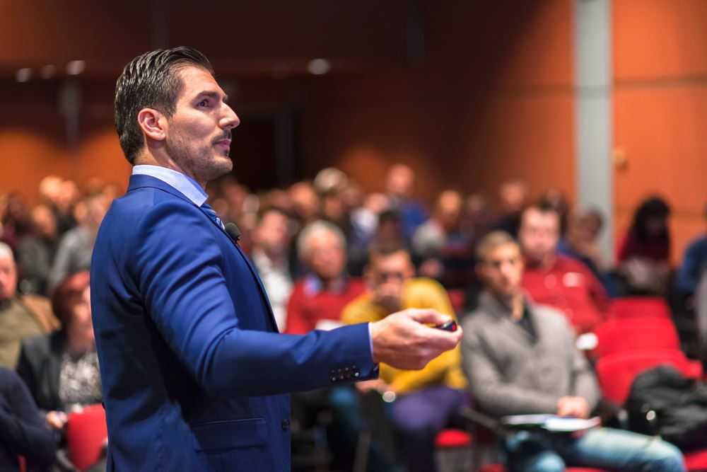 businessman presenting a slideshow in front of a large audience